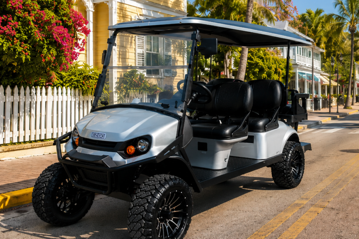 A golf cart parked on a sunny street lined with palm trees and colorful houses.