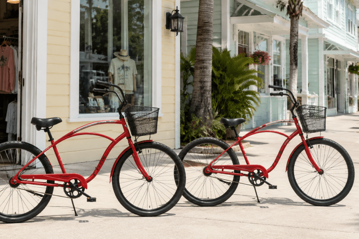 Two red bicycles parked on a sidewalk near shops.