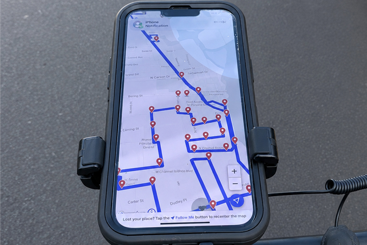 Smartphone on bike showing map with marked route on screen.